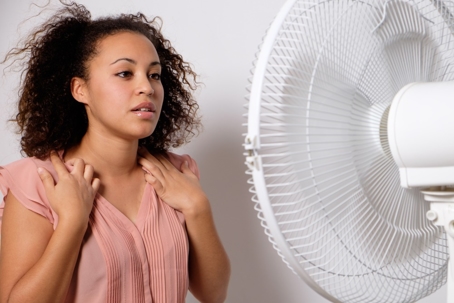 A woman enjoying a cool breeze from a fan
