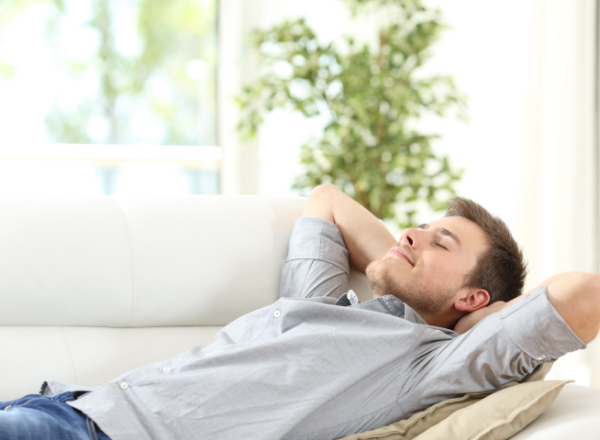 Man laying on couch smiling and relaxing