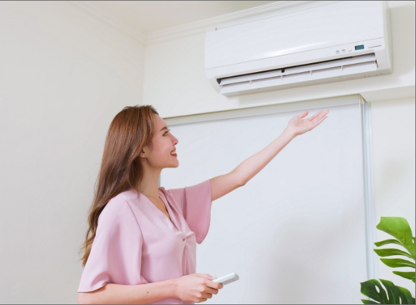Woman with her hand under her ductless mini split system checking the temperature
